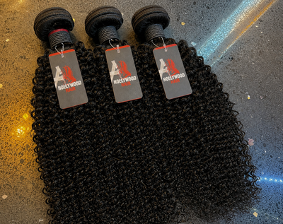Three water wave bundles of human hair  with Hollywood hair tags lying on a reflective surface.